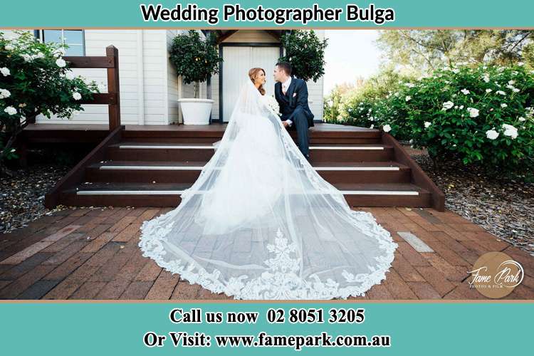 Photo of the Bride and the Groom looking each other while sitting at the staircase Bulga NSW 2330