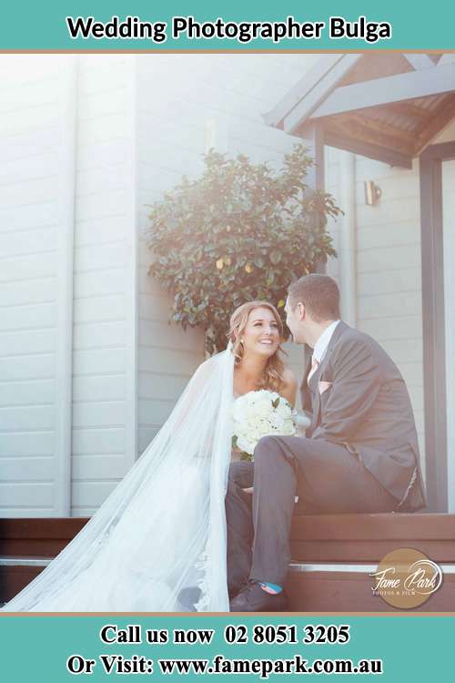 Photo of the Bride and the Groom looking each other while sitting at the staircase Bulga NSW 2330