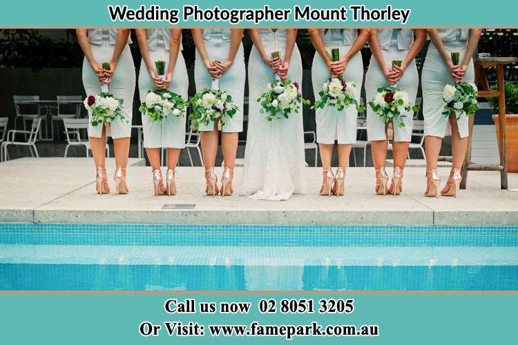 Behind photo of the Bride and the bridesmaids holding flowers near the pool Mount Thorley NSW 2330