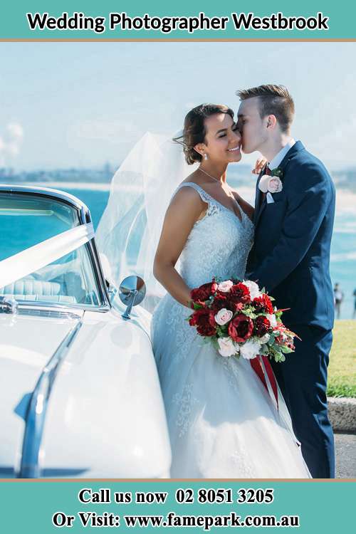 Photo of the Groom kiss the Bride besides the bridal car Westbrook NSW 2330